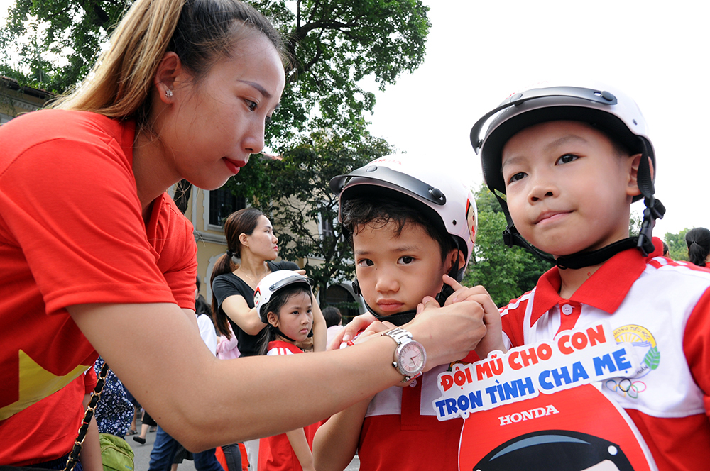 Chị Vân (quận Hoàn Kiếm, Hà Nội) ân cần đội mũ bảo hiểm cho con trai Nhật Minh.