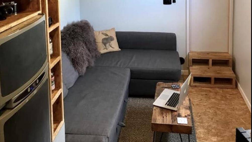 Phòng khách có một chiếc ghế bành và đầy đủ không gian cho bạn bè, gia đình đến thăm