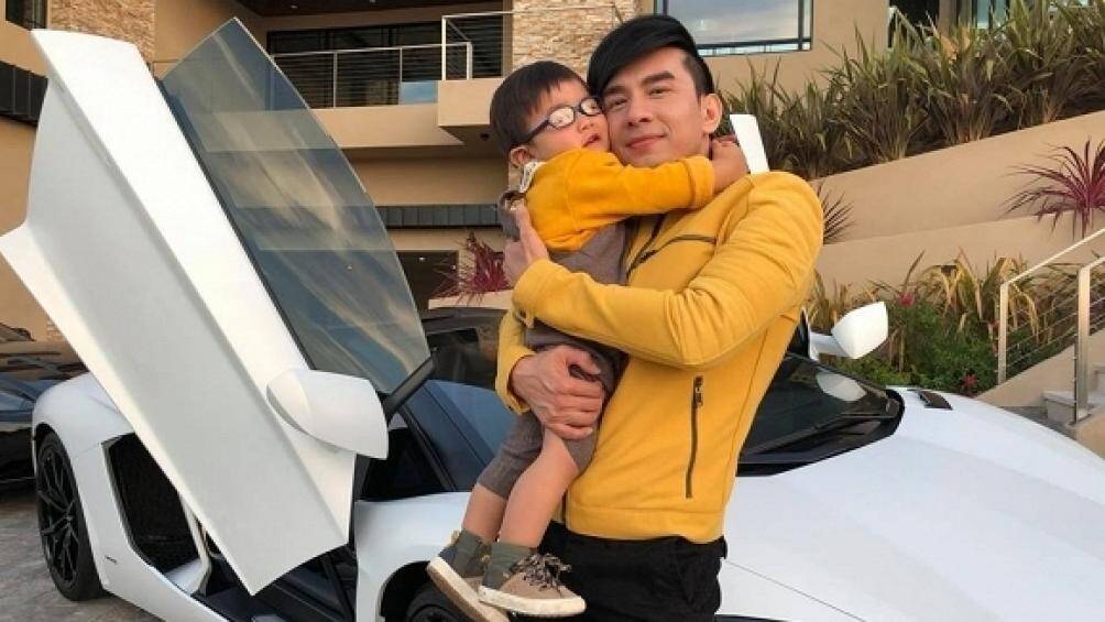 Đan Trường bế con tạo dáng bên siêu xe. Bức ảnh khéo khoe được gia đình hạnh phúc và cơ ngơi "khủng" của ca sĩ tại Mỹ
