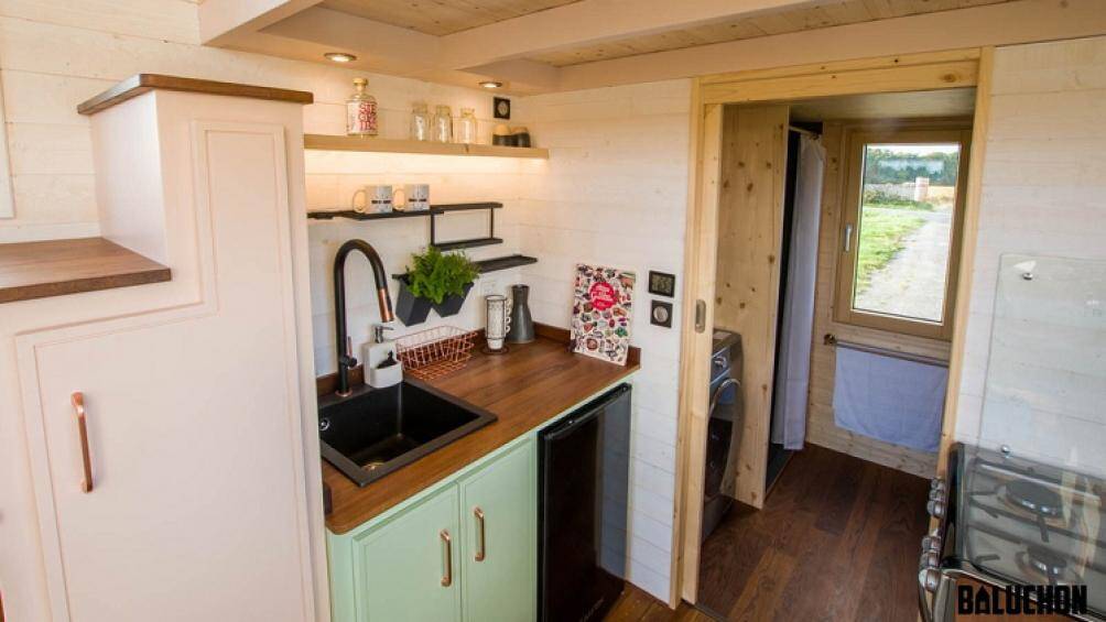 Không gian này là nhà bếp, bao gồm hai mặt bàn, nhiều không gian lưu trữ, một tủ lạnh lớn, bồn rửa và bếp nấu với lò nướng