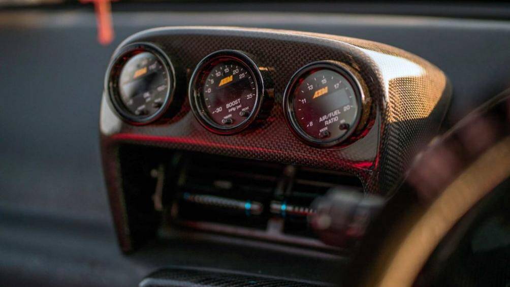 Xe được bổ sung thêm ba đồng hồ đo AEM Electronics được đặt trong một hộp đồng hồ đo Bee * R, đường gờ gạch ngang bằng sợi carbon