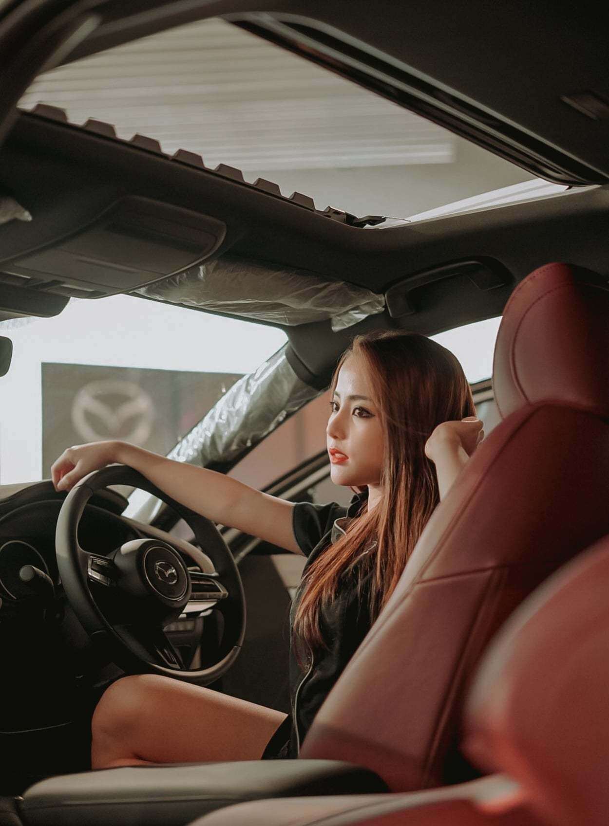 Cô diện bộ đầm xanh nổi bật trên tông nền màu sẫm trong nội thất xe