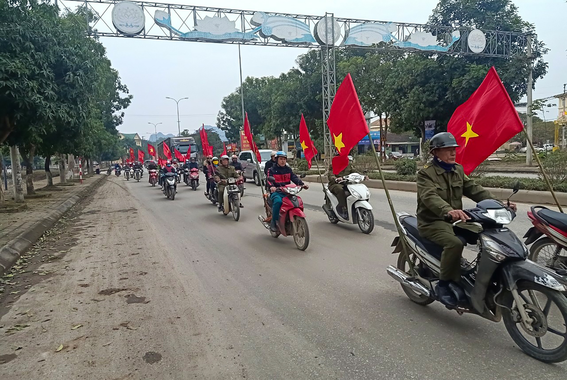 Người dân Anh Sơn mang theo cờ Đảng và cờ Tổ quốc diễu hành trên đường