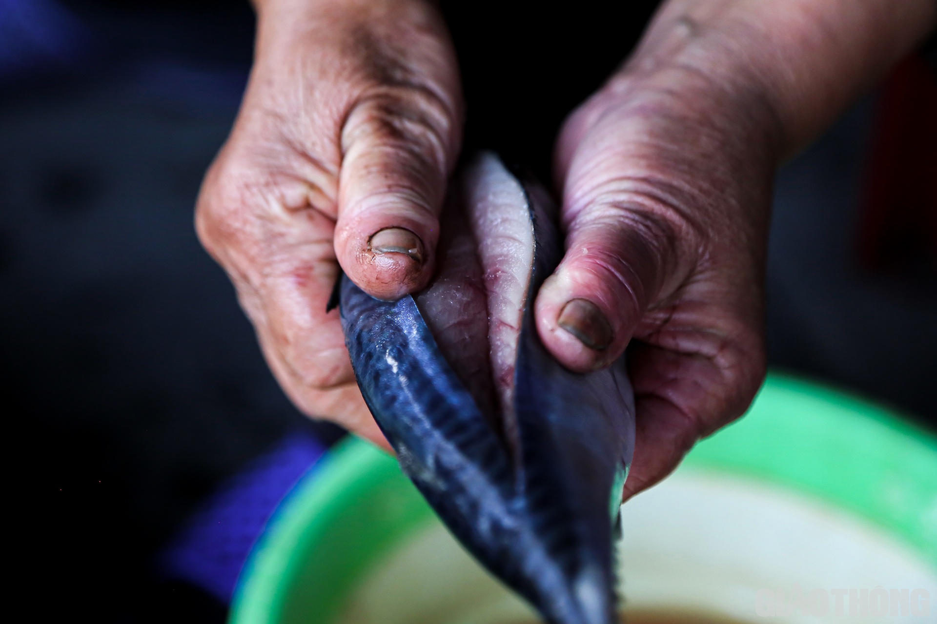 Người thợ nướng cá dùng tay nắn nhẹ để phần rạch hở ra, khoe những thớ thịt tươi ngon bên trong con cá