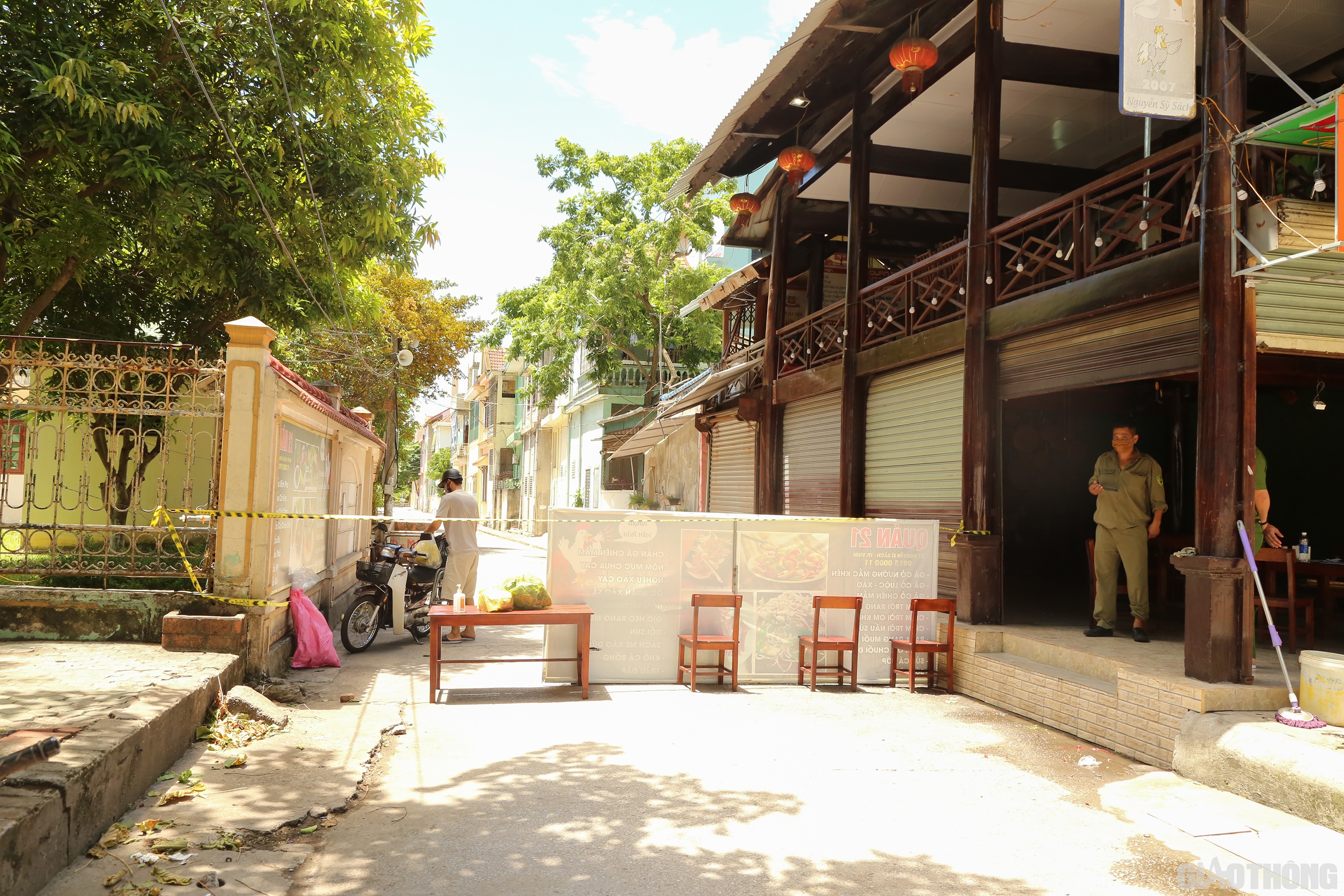 Người thân của chị Thủy ra nhận đồ tiếp tế, các bên đều giữ khoảng cách từ rất xa. Lực lượng chức năng giám sát việc giữ khoảng cách giữa các bên.  Ảnh: Sỹ Hòa