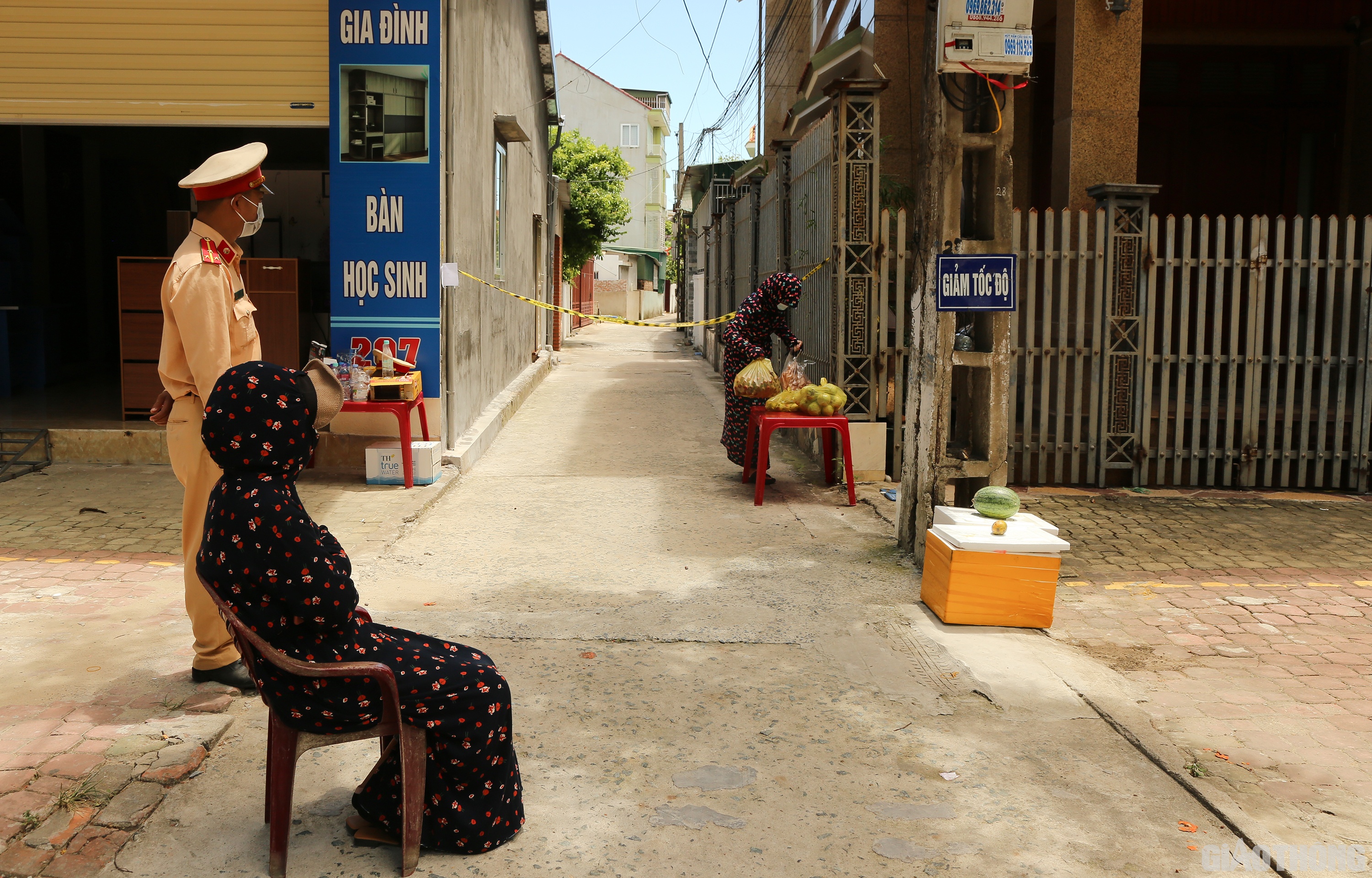 Một người phụ nữ trong khu phong tỏa ở phường Hà Huy Tập, TP Vinh trùm kín người để tránh nắng đi bộ ra chốt phong tỏa ở ngõ 207 đường Hà Huy Tập nhận đồ ăn đặt mua được ship đến. (Ảnh Sỹ Hòa)