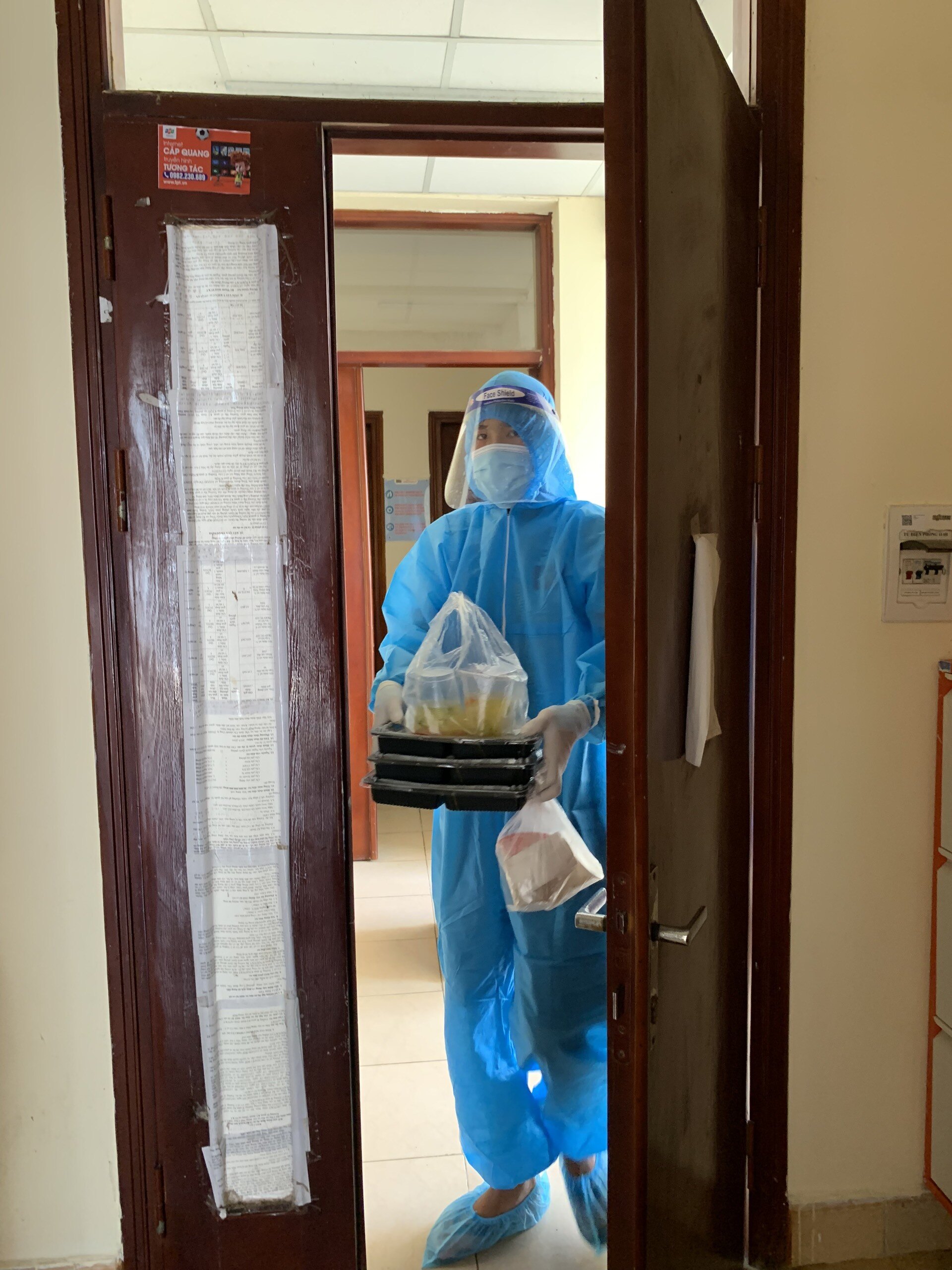 Lực lượng chức năng giao đồ ăn mặc quần áo bảo hộ nhằm đảm bảo phòng, chống dịch bệnh trong khu cách ly.