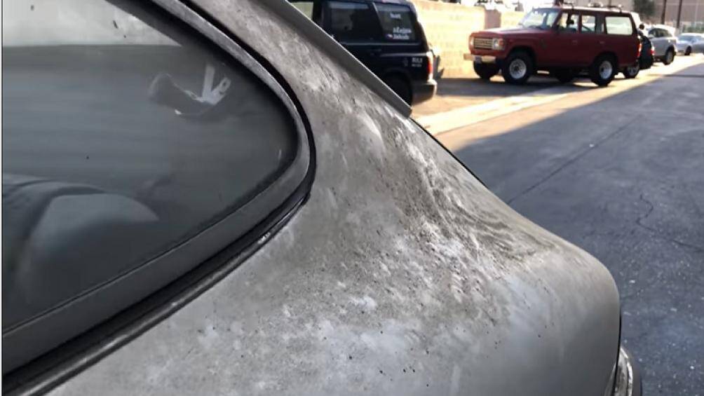 Thân xe bị phủ một lớp bụi dày, lốp xe có dấu bùn đất, còn đèn pha bên phải đã bị vỡ đôi chỗ, cần được lau rửa chi tiết