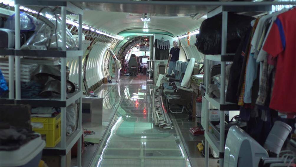 Ở một bên của sofa, kệ và thanh treo được tận dụng để tạo thành tủ quần áo đơn giản