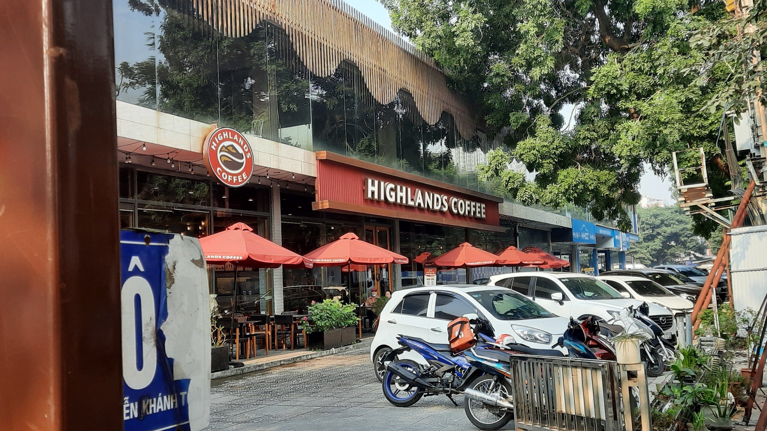 Ngay cạnh đó là quán cà phê treo biển Highlands Coffee vẫn hoạt động với người ra vào thường xuyên.