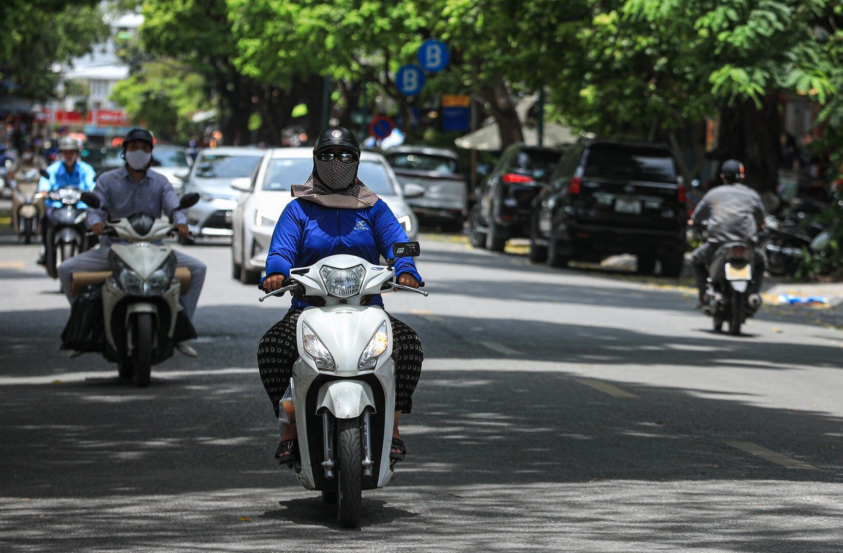 Đa phần những người di chuyển bằng xe máy trên đường đều phải chùm áo, quần kín người để tránh cái nắng gay gắt.
