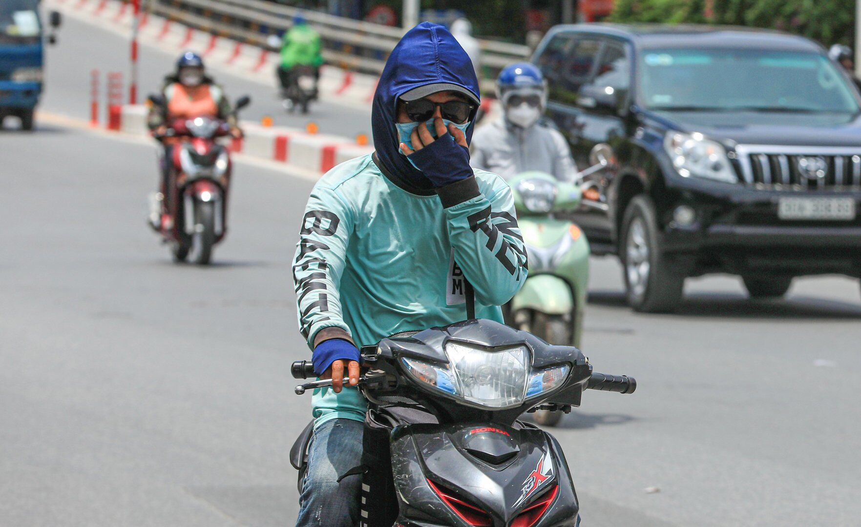 Người tham gia giao thông phải sử dụng áo, mũ, găng tay để chống chọi với cái nắng gay gắt.