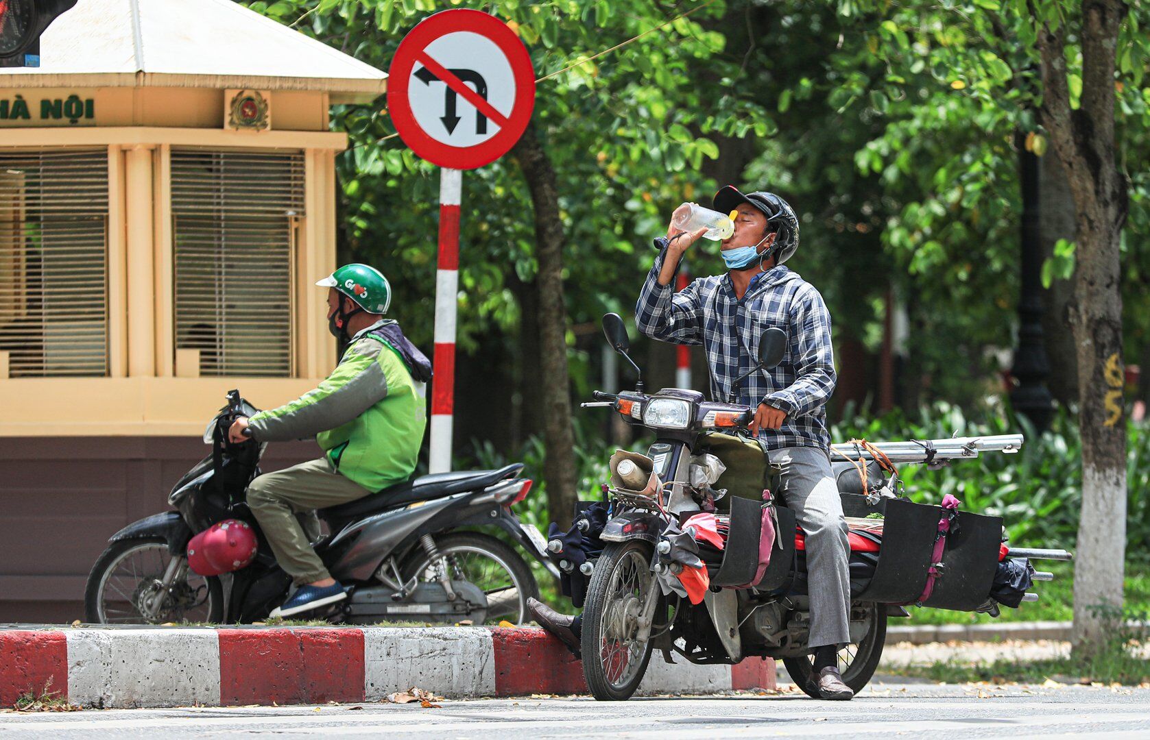 Một người tham gia giao thông bằng xe máy khi dừng đèn đỏ cũng tranh thủ bổ sung nước vào cơ thể.