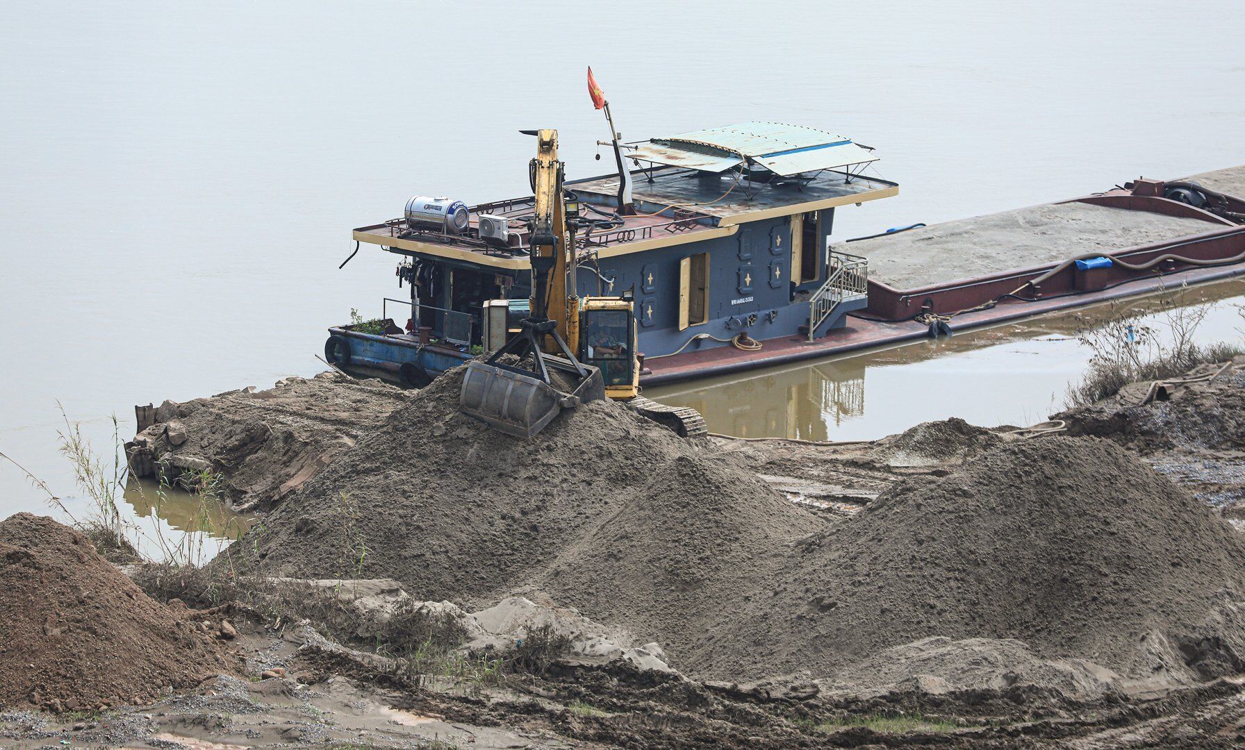 Tại khu đất bãi sông Hồng, đoạn qua địa phận xã Vĩnh Ngọc, dễ dàng ghi nhận cảnh tượng nhiều tàu chở cát và máy xúc tấp nập hoạt động.