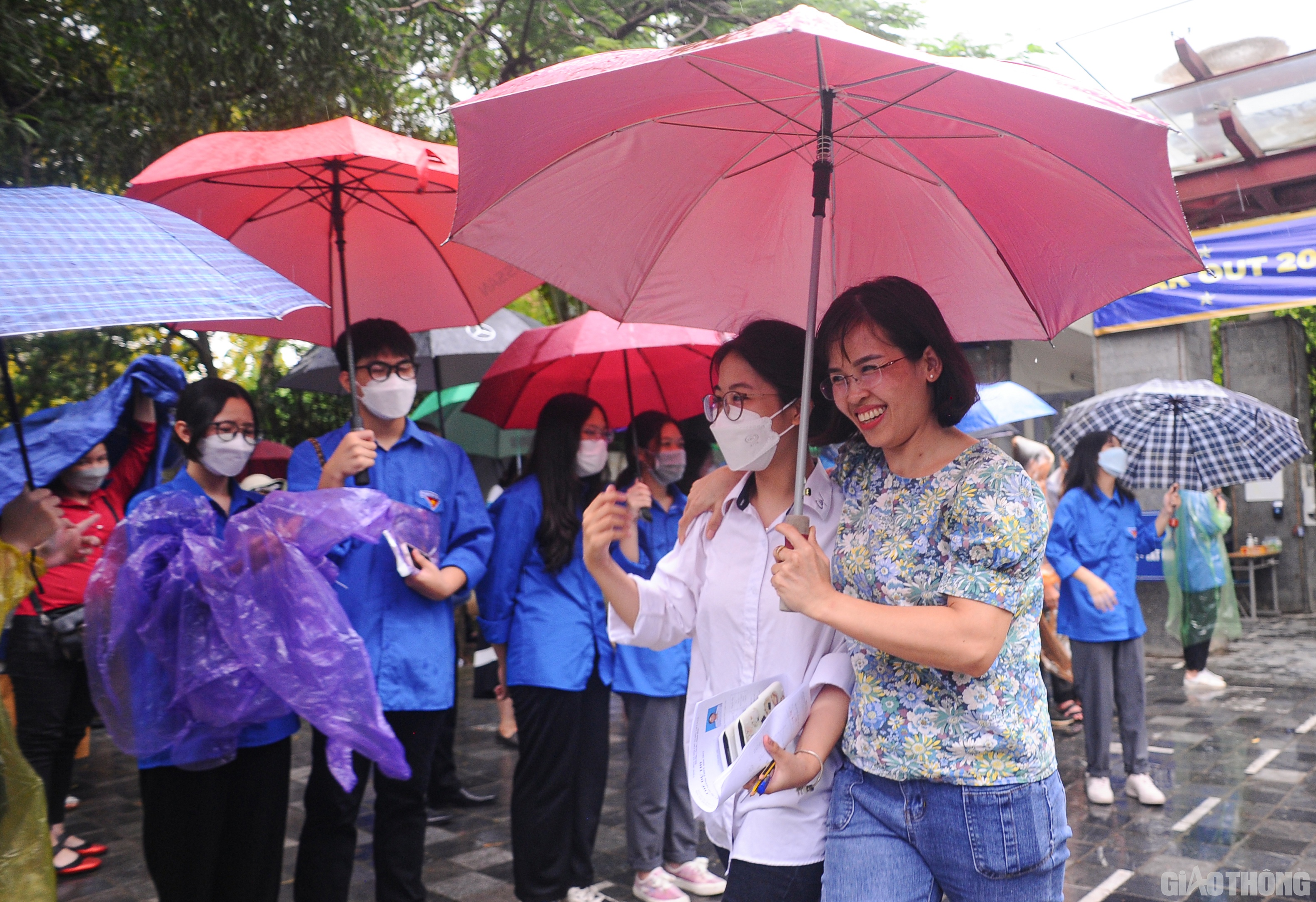 Các phụ huynh cũng nhanh chóng tiến vào sát cổng trường che ô cho con.