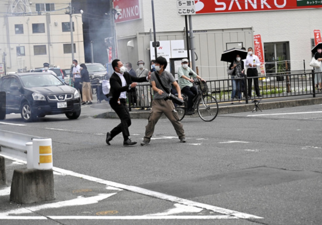 Một cận vệ tiếp cận nghi phạm bắn cựu Thủ tướng Nhật Bản Abe Shinzo. Theo truyền thông Nhật Bản, sau khi tấn công, nghi phạm không chạy trốn mà đứng nhìn ông Abe.