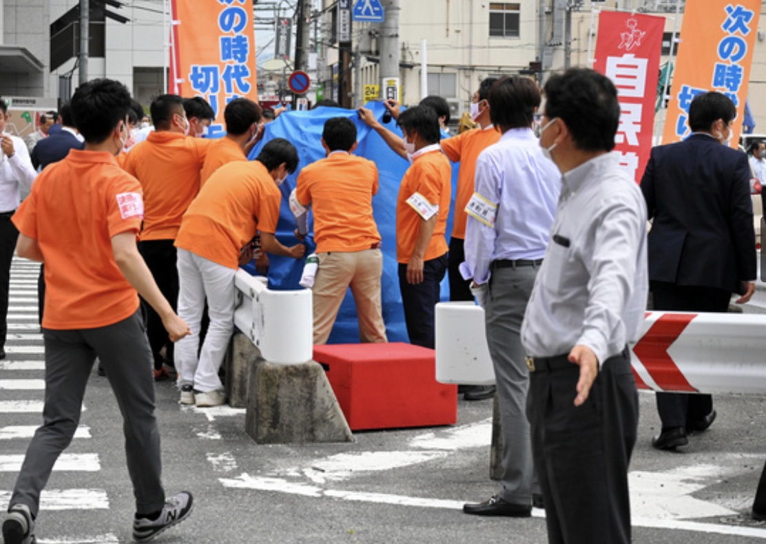 Lực lượng cứu hộ dùng bạt che chắn trong lúc nhân viên y tế sơ cứu cho ông Abe. Ảnh - Asahi