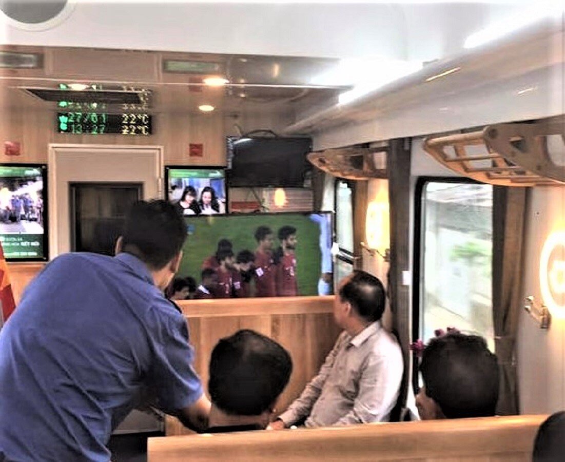 Hành khách mê môn thể thao vua - bóng đá sẽ không lo bỏ lỡ  những trận cầu gay cấn vì có thể xem tại toa hàng ăn trên tàu hoặc sử dụng wifi miễn phí trên tàu xem trực tiếp bằng điện thoại smartphone. Ảnh: Hành khách xem bóng đá truyền hình trực tiếp trên toa hàng ăn