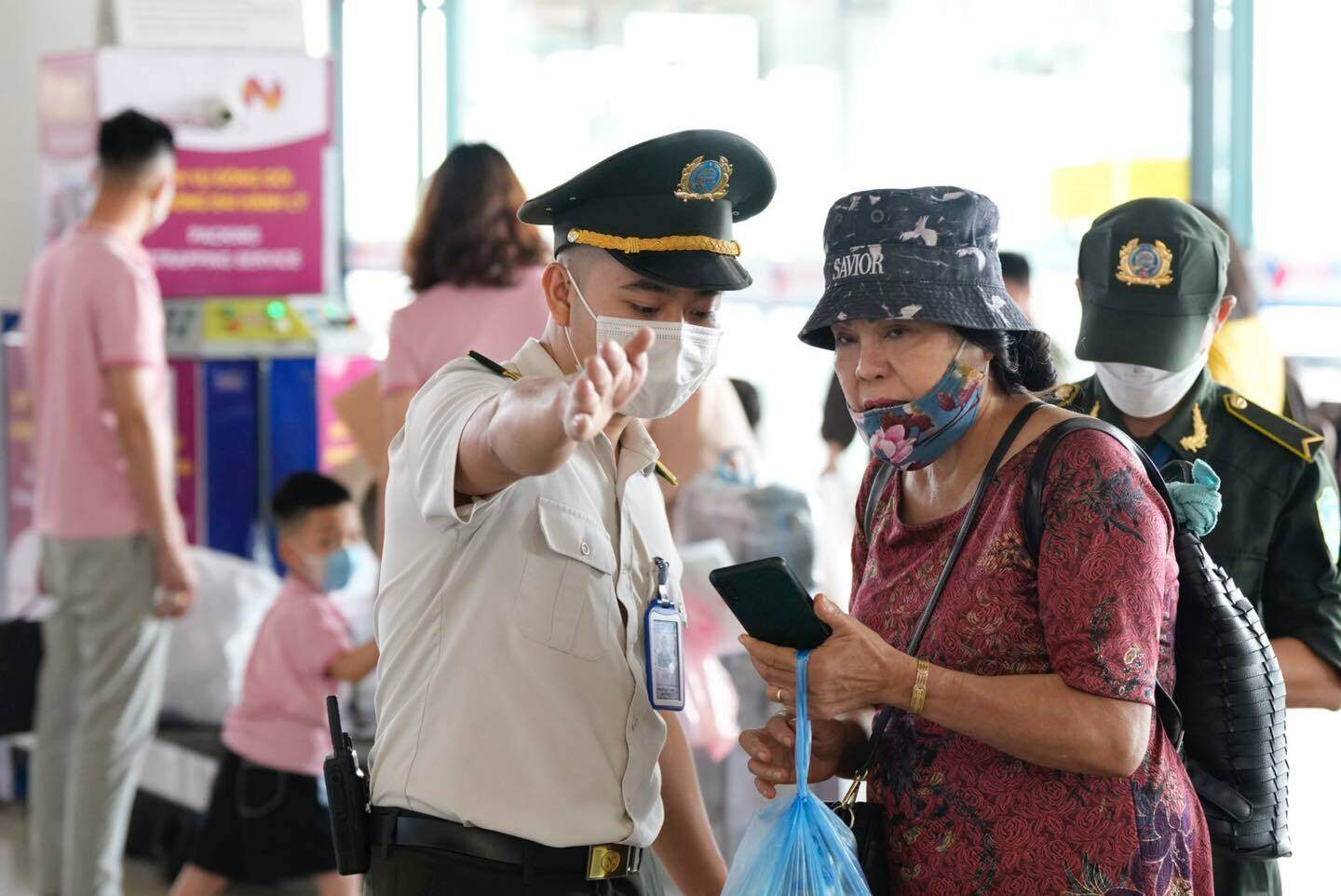 Nhân viên an ninh hướng dẫn cho một hành khách lớn tuổi