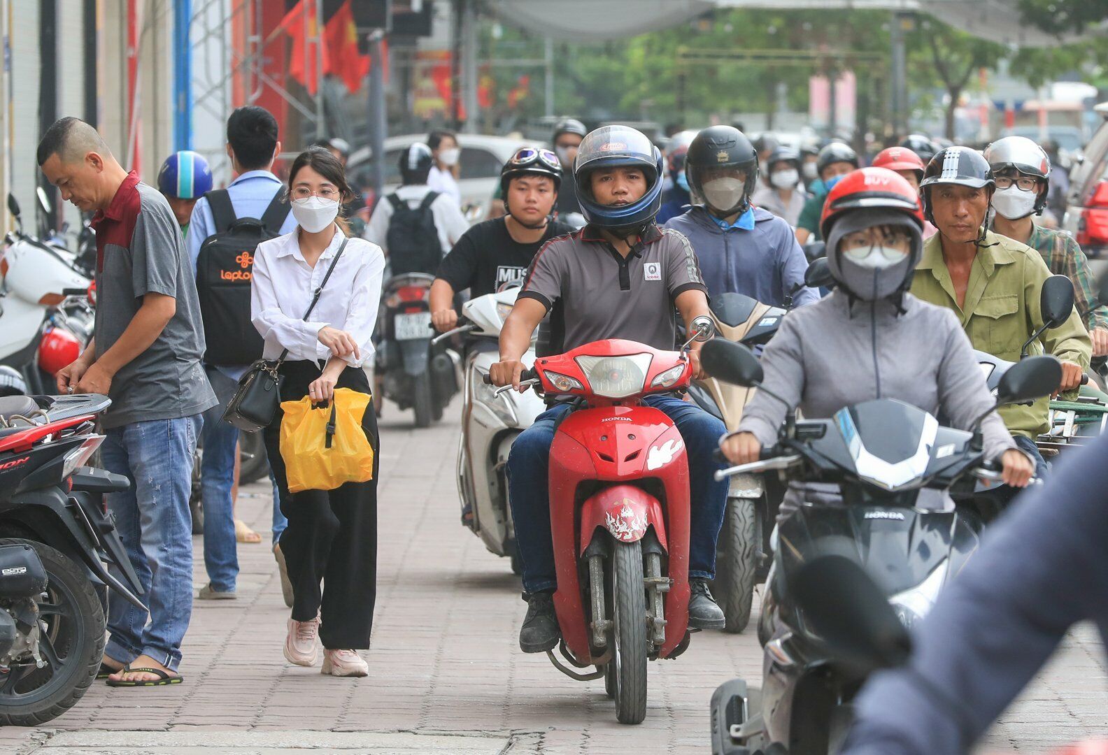 Tại đường Nguyễn Xiển, nhiều người đi xe máy leo lên vỉa hè để đi nhanh hơn, lấn chiếm đường dành cho người đi bộ.