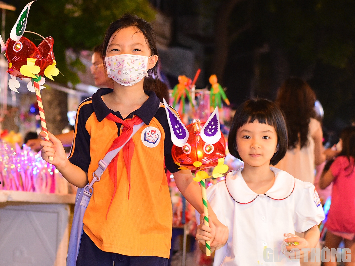 Hai em nhỏ thích thú cầm trên tay món đồ chơi sặc sỡ.