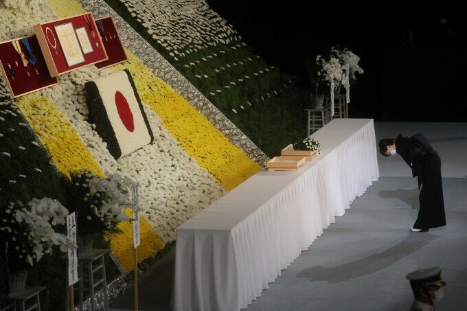 Phu nhân Akie Abe đặt hoa, cúi đầu tiễn biệt chồng.