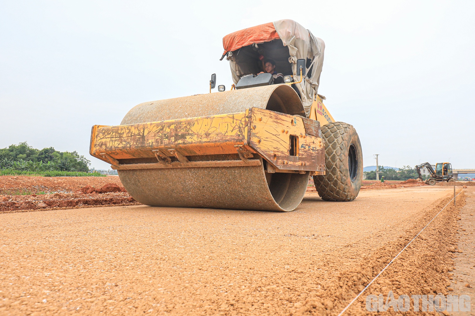 “Tuy nhiên, những ngày gần đây, nhà thầu đã chấp nhận mua vật liệu từ những mỏ xa hơn (cách công trường 27 km) thay vì các mỏ dự kiến lấy ban đầu (cách công trường 15 km) để tăng tốc, bù những phần việc bị chậm. Năng suất thi công CTB đã được đẩy lên 800 m3/ngày thay vì 300 - 400 m3 như thời gian trước. Việc thi công CTB hiện đã được 1 km/7,3 km, dự kiến sẽ hoàn thành vào ngày 6/11”, ông Bắc thông tin. Trong ảnh: nhà thầu thi công cấp phối đá dăm tại Km294+880.
