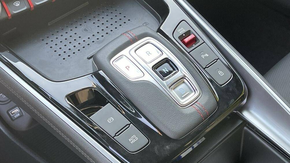 Bên dưới là sạc điện thoại thông minh không dây, các nút bấm chuyển số, phanh tay điện tử, tính năng tự động giữ phanh tạm thời và bộ bàn đạp bằng kim loại