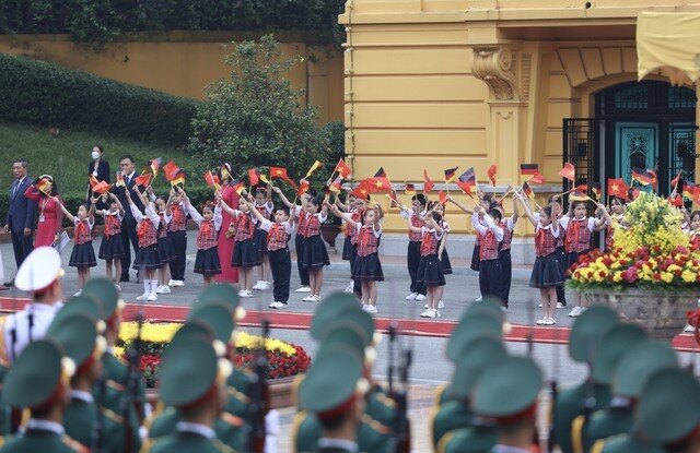 Dự án "hải đăng" của hai nước trong lĩnh vực giáo dục - đào tạo là Trường Đại học Việt Đức, được thành lập từ tháng 9/2008 tại Thành phố Hồ Chí Minh, hoạt động theo mô hình của đại học Đức. 
Dự án xây dựng trụ sở Trường Đại học Việt Đức tại huyện Bến Cát, tỉnh Bình Dương với nguồn vốn vay trị giá khoảng 200 triệu USD của Ngân hàng Thế giới đã hoàn thành vào tháng 5/2021.
Trong ảnh, các em học sinh vẫy cờ hoa chào đón Đoàn đại biểu CHLB Đức thăm Việt Nam - Ảnh: VGP/Nhật Bắc