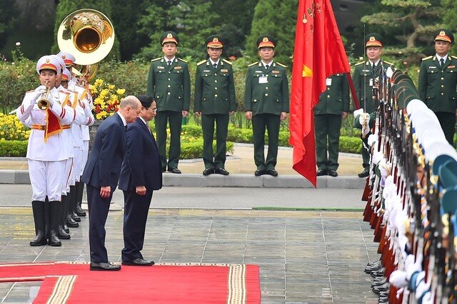 Trong chuyến thăm Việt Nam của Thủ tướng Đức Angela Merkel (tháng 10/2011), Thủ tướng hai nước đã ký Tuyên bố chung Hà Nội về việc thiết lập quan hệ Đối tác chiến lược, trong đó đề ra các mục tiêu và biện pháp cụ thể tăng cường hợp tác trong các lĩnh vực ưu tiên.
Đức là đối tác thương mại lớn nhất của Việt Nam ở châu Âu (chiếm gần 20% xuất khẩu của Việt Nam sang EU) và cũng là cửa ngõ trung chuyển quan trọng của hàng hóa Việt Nam sang các thị trường khác ở châu Âu.
Trong ảnh, hai nhà lãnh đạo thực hiện nghị thức chào Quốc kỳ hai nước - Ảnh: VGP/Nhật Bắc