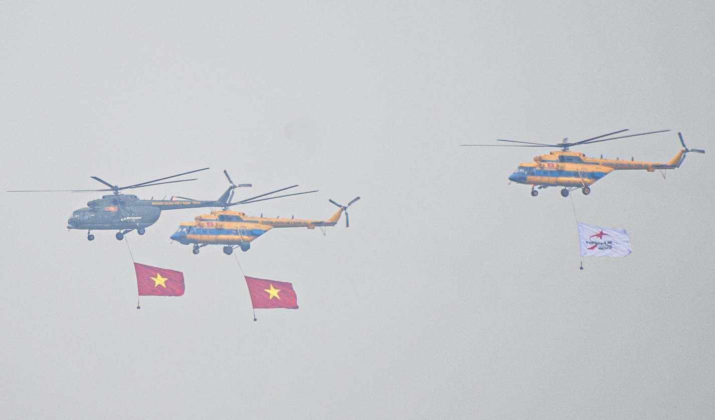 Dàn trực thăng Mi mang theo cờ Tổ quốc và cờ biểu trưng của triển lãm Quân sự quốc tế Việt Nam 2022 bay trình diễn trên bầu trời Thủ đô.