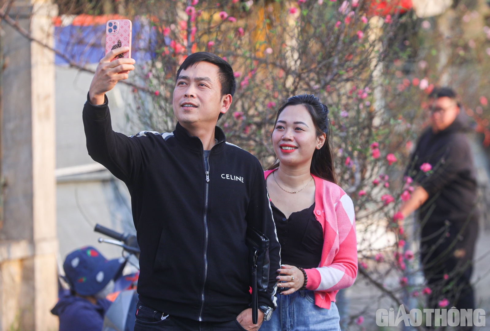 Nhiều người vừa dạo bước ngắm hoa vừa tranh thủ lưu lại khoảnh khắc đẹp bên cành đào đầu mùa.