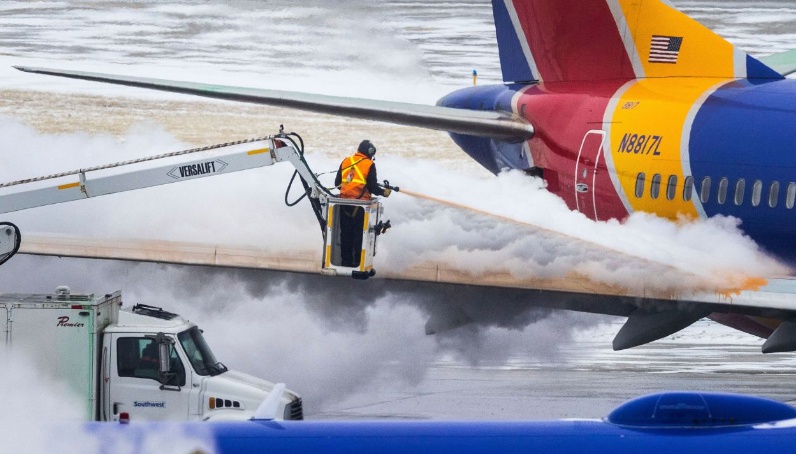 Nhân viên kỹ thuật làm tan băng bên ngoài máy bay trước khi phương tiện chuẩn bị đón khách. Ảnh - CNN