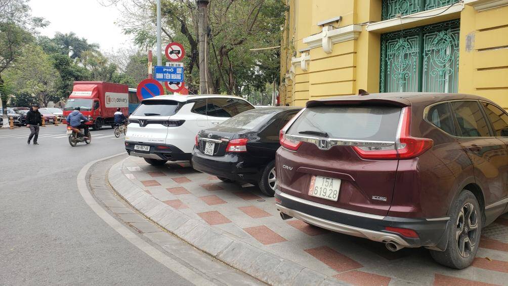 Tại vỉa hè ở đường Đinh Tiên Hoàng, nhiều xe ô tô dừng đỗ kín khiến người đi bộ phải đi xuống lòng đường, ảnh hưởng đến ATGT.