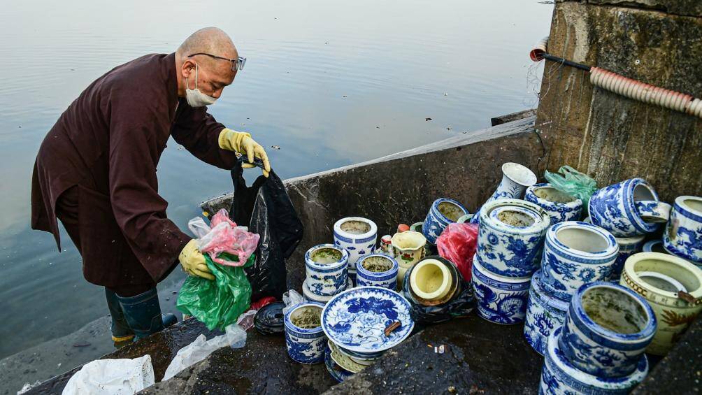 Tại bậc l&ecirc;n xuống của hồ T&acirc;y, thầy Th&iacute;ch Tịnh Gi&aacute;c (ch&ugrave;a Ph&uacute;c Sơn, x&atilde; Kim Sơn, Gia L&acirc;m) đang vất vả thu dọn r&aacute;c thải, nilon ven hồ.