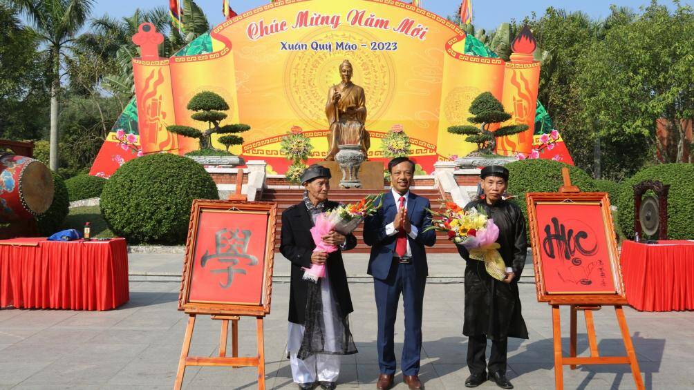 2 nghệ nhân viết chữ "Học" bằng quốc ngữ và chữ nho để tặng ngành giáo dục huyện Vĩnh Bảo.