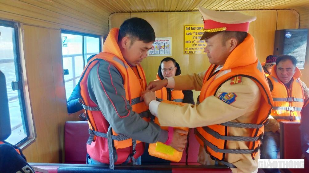 Cán bộ chiến sĩ Đội CSGT đường thủy hướng dẫn người dân thao tác mặc áo phao đúng cách.