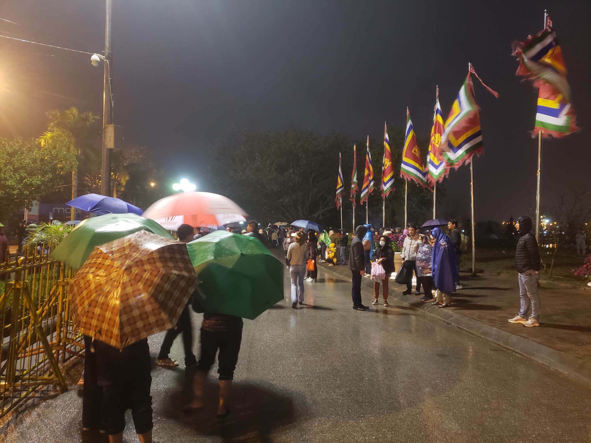 Sau 20h, tiết trời mưa nặng hạt, người dân vẫn che ô đứng ngoài khu vực barie chờ giây phút được nhận lá ấn.