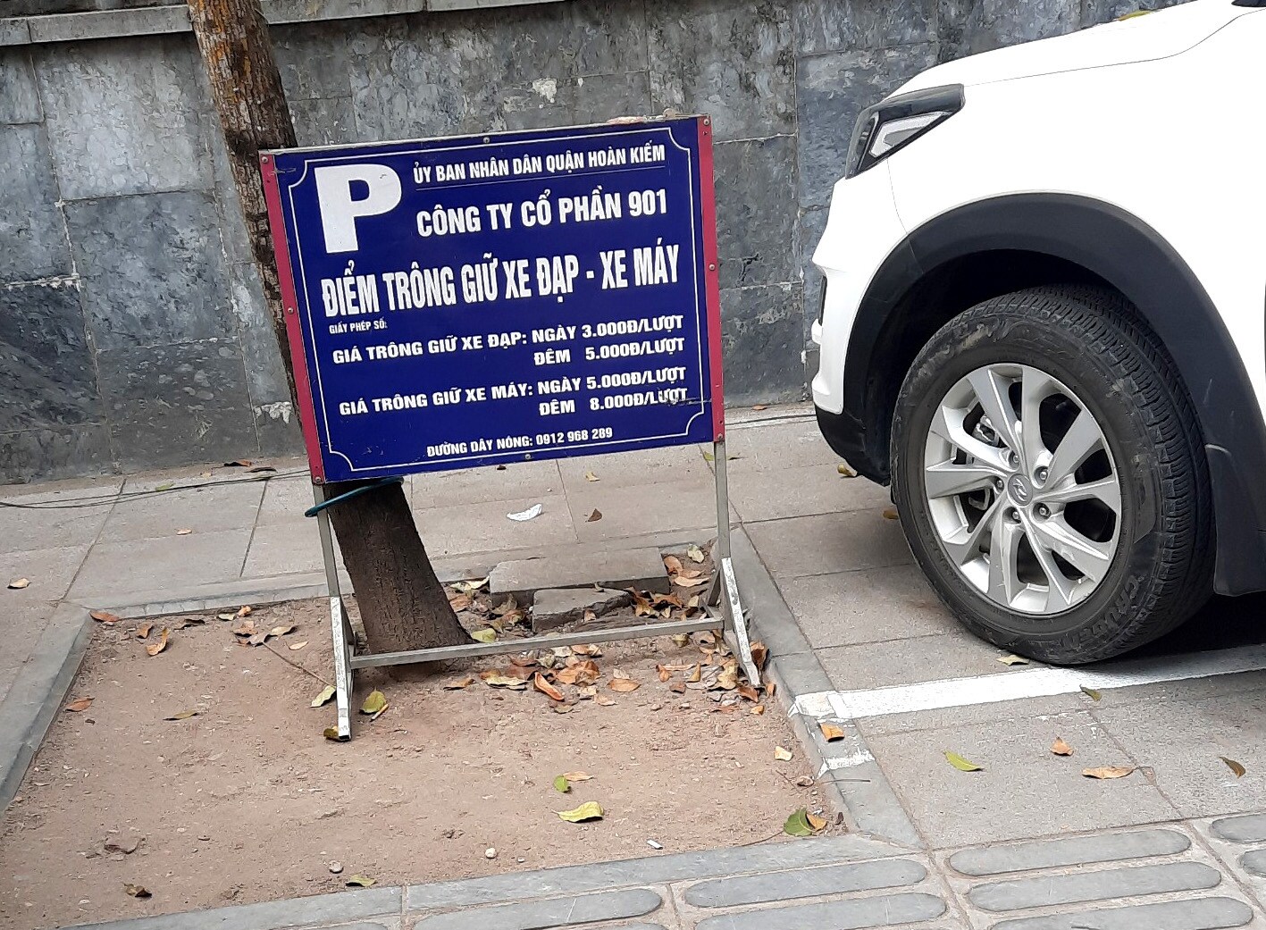 Tại vỉa hè trên phố Trần Bình Trọng có bảng hiệu ghi điểm trông giữ xe đạp - xe máy của Công ty Cổ phần 901.