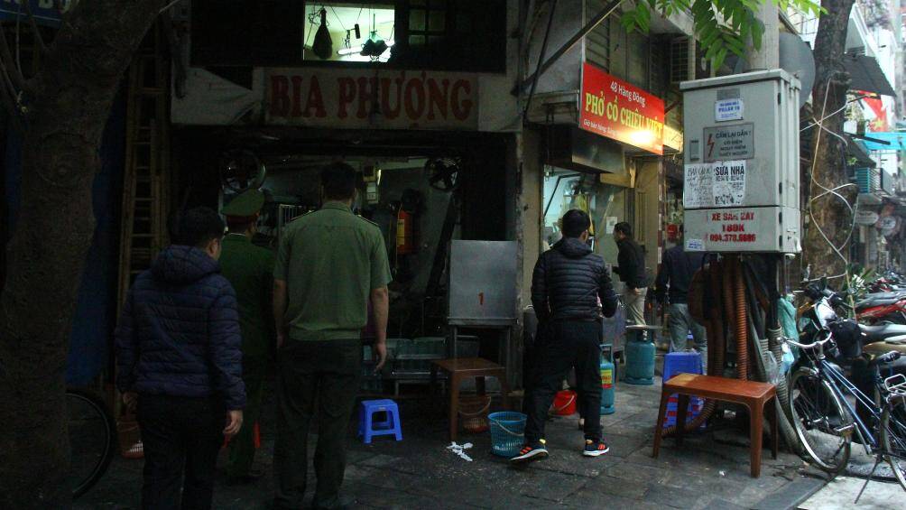 Người dân bê vội bát phở khi tổ công tác nhắc nhở về việc chủ quán phở kê bàn ghế trên vỉa hè ở phố Hàng Đồng.