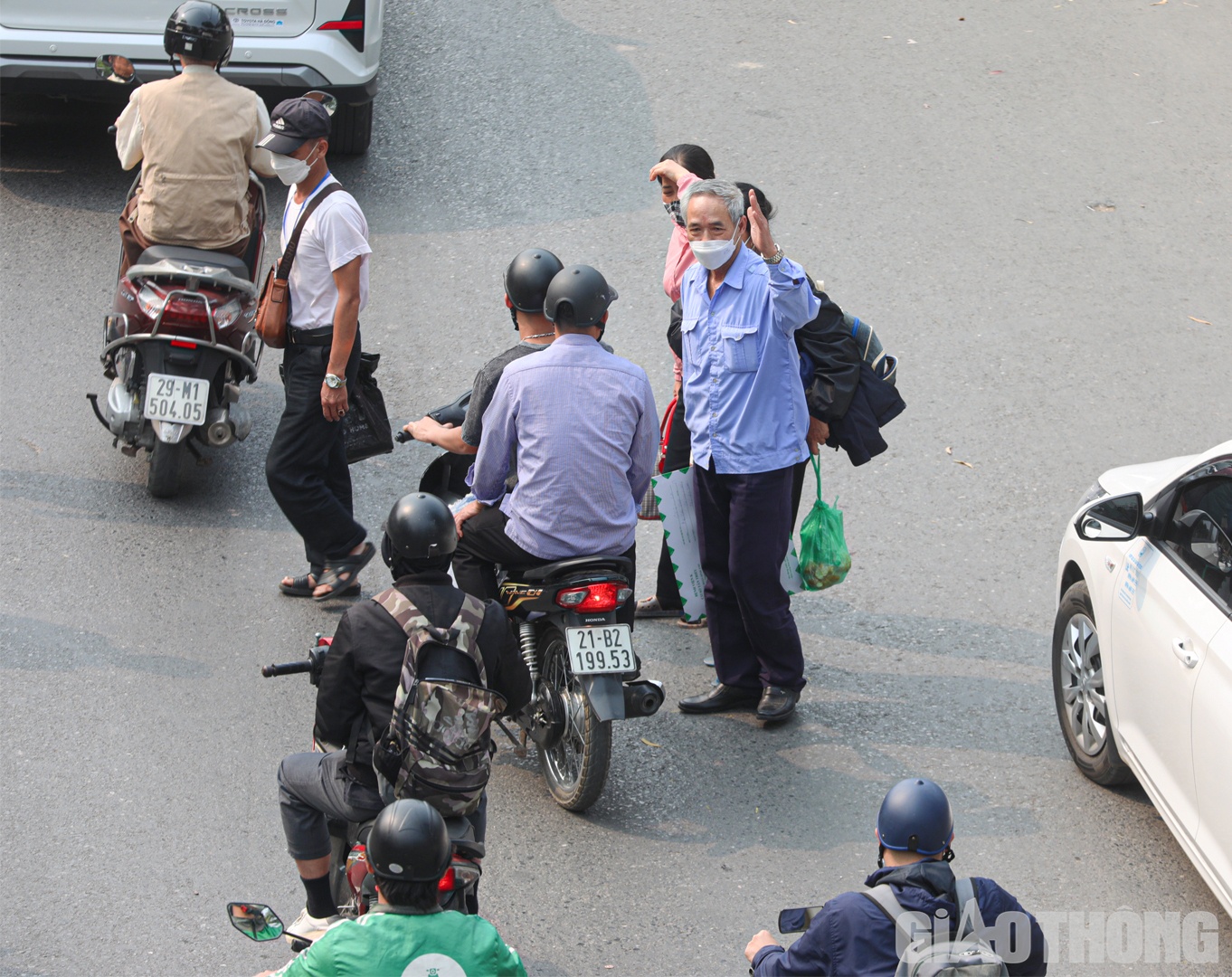 Từng nhóm người dàn hàng ngang, dắt díu nhau lách qua đầu ô tô, xe máy đang di chuyển.