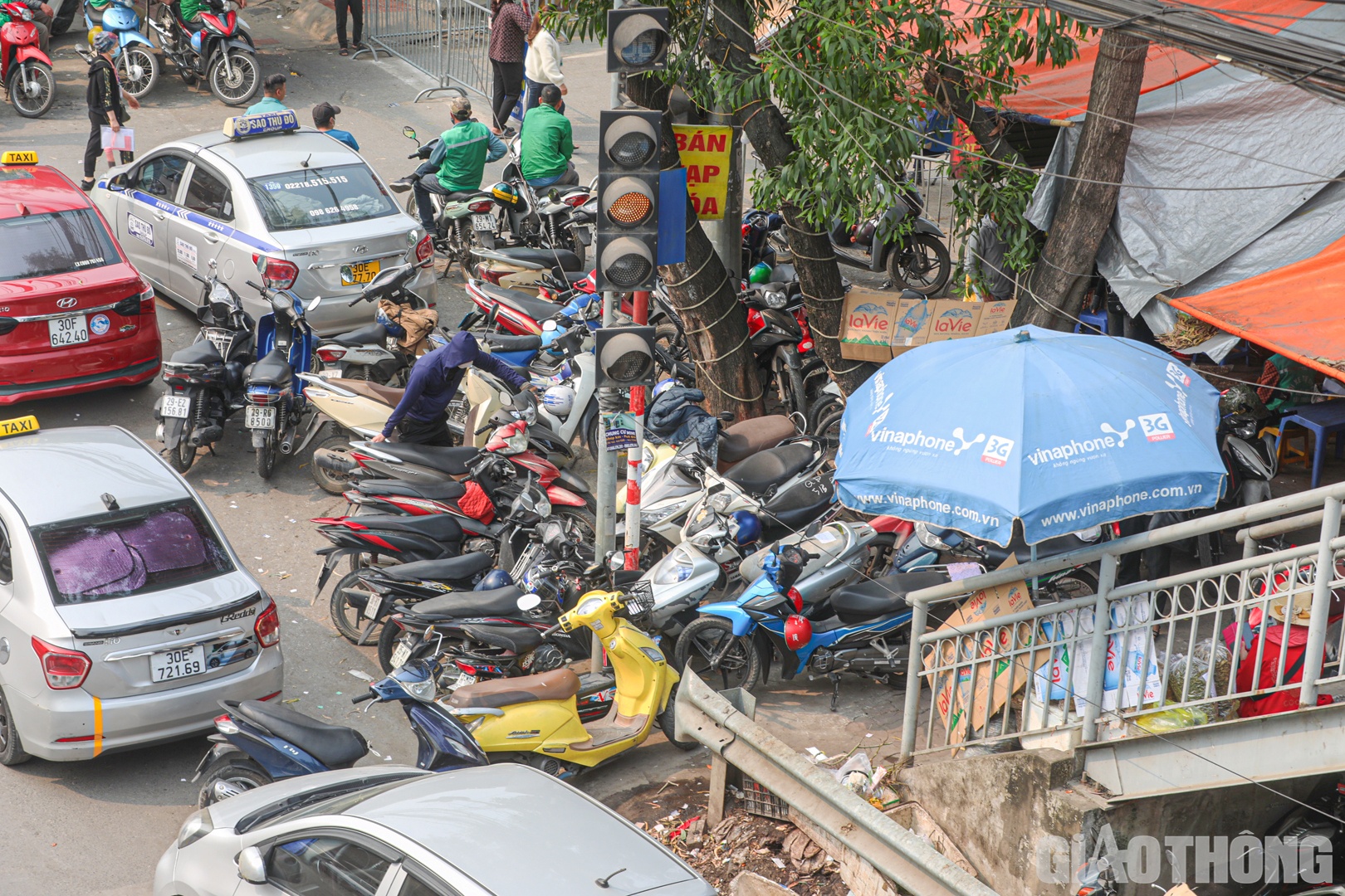 Ngay tại chân cầu bộ hành, hàng loạt taxi, xe máy… dừng đỗ gây cản trở lối lên của người đi bộ.