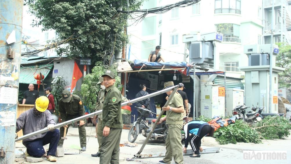 Lực lượng chức năng tháo dỡ, thu giữ các đồ vật lấn chiếm vỉa hè ở khu vực đường Nguyễn Xiển.