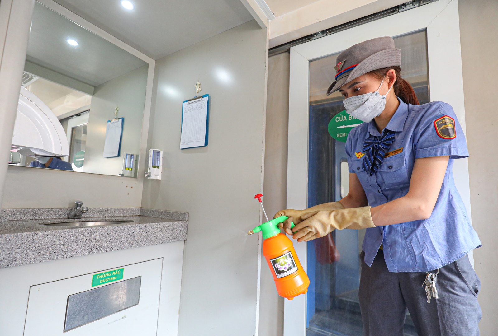 Không chỉ các trang thiết bị trực tiếp phục vụ hành khách, đường sắt còn tăng cường công tác vệ sinh, công tác phòng dịch Covid-19. Đoàn Tiếp viên đường sắt Hà Nội yêu cầu nhân viên trên các đoàn tàu đeo khẩu trang và nhắc nhở hành khách đeo khẩu trang trên hành trình. Nhân viên phải thường xuyên thu dọn vệ sinh, khử khuẩn trên tàu tại các vị trí thường xuyên tiếp xúc như mặt bàn, tay nắm cửa... (Ảnh: Vệ sinh viên trên tàu xịt khử khuẩn khu vực rửa mặt, chuẩn bị xà phòng rửa tay)
