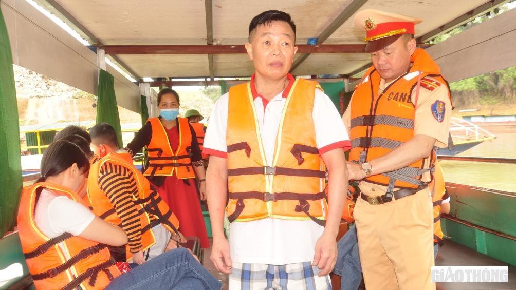 Đội CSGT đường thủy, Phòng CSGT, Công an tỉnh Yên Bái hướng dẫn người dân mặc áo phao, dụng cụ nổi nhằm đảm bảo an toàn khi đi du lịch trên hồ Thác Bà