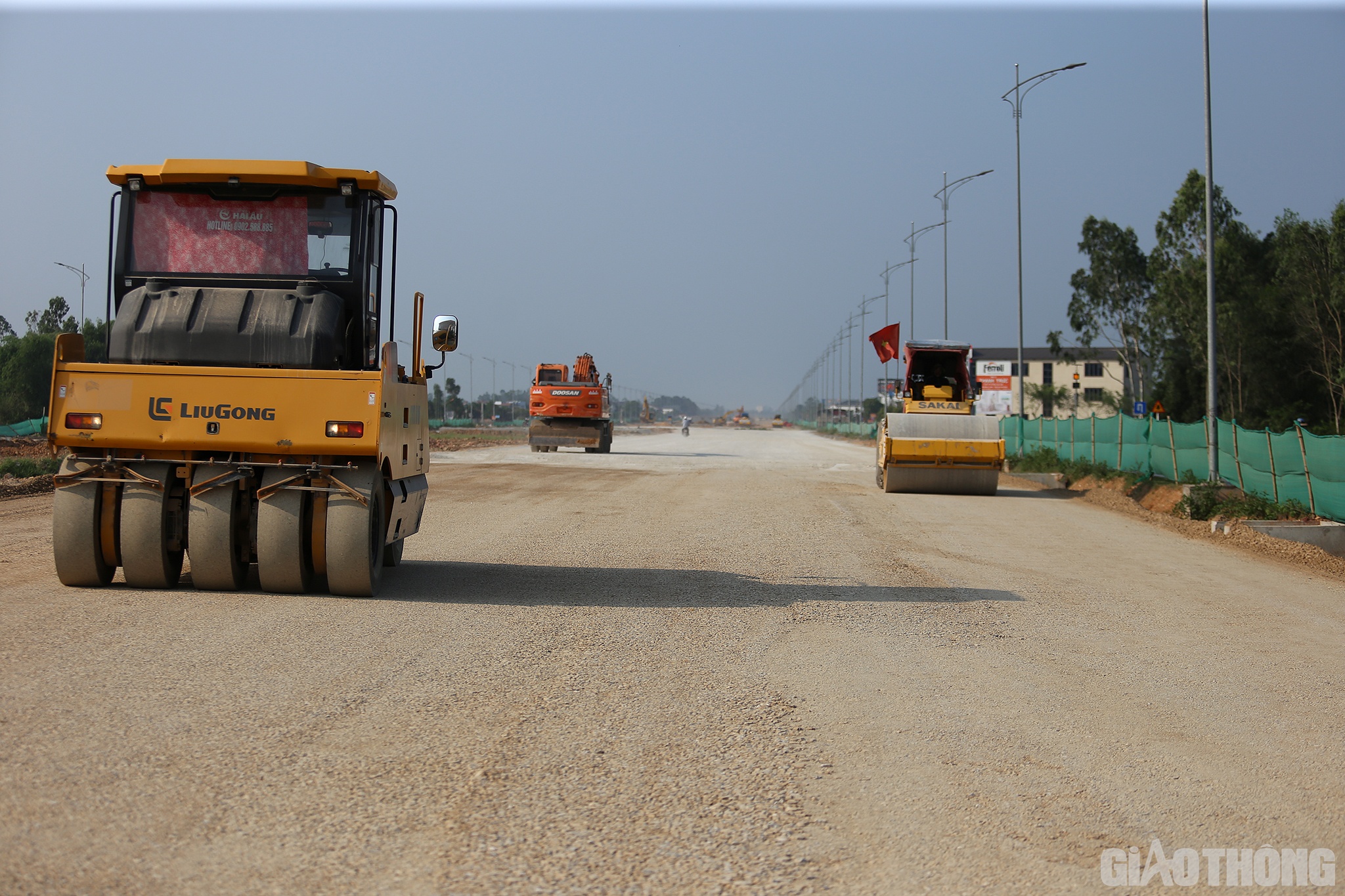 Tại đoạn Km 3+300, các loại như máy múc, máy lu, máy gạt hoạt động hết công suất, cùng nhiều xe vận tải đất, cấp phối đá dăm nhộn nhịp ra vào