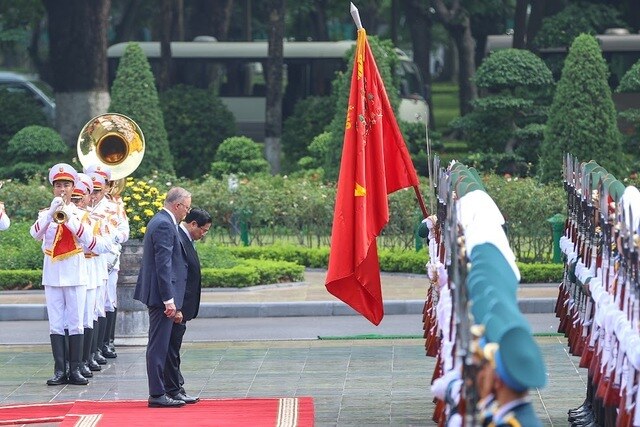 Hai Thủ tướng chào Quân kỳ Quyết thắng tại lễ đón. (Ảnh: VGP/Nhật Bắc)