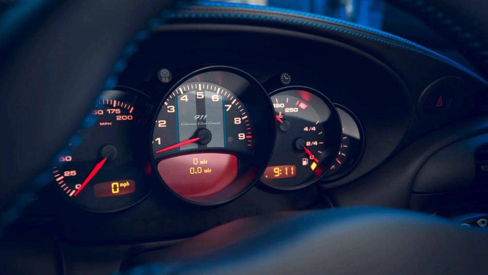 Bộ đồng hồ đo vòng tua máy có hai sọc màu xám với các đường kẻ ở hai bên màu xanh Club và logo “911 Classic Club Coupe”