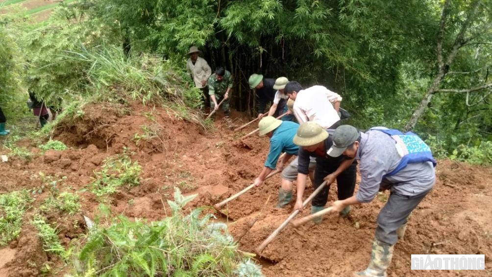Các lực lượng tham gia san gạt lở đất đường giao thông nông thôn để người dân đi lại an toàn.