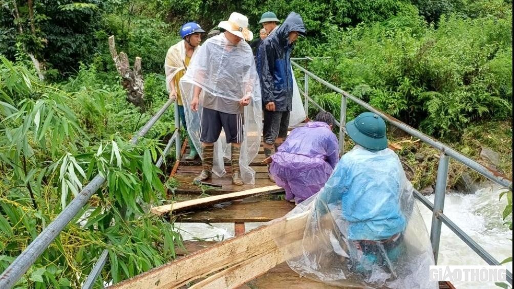 Lực lượng dân quân tham gia sửa chữa cầu treo bị hư hỏng do lũ gây ra.